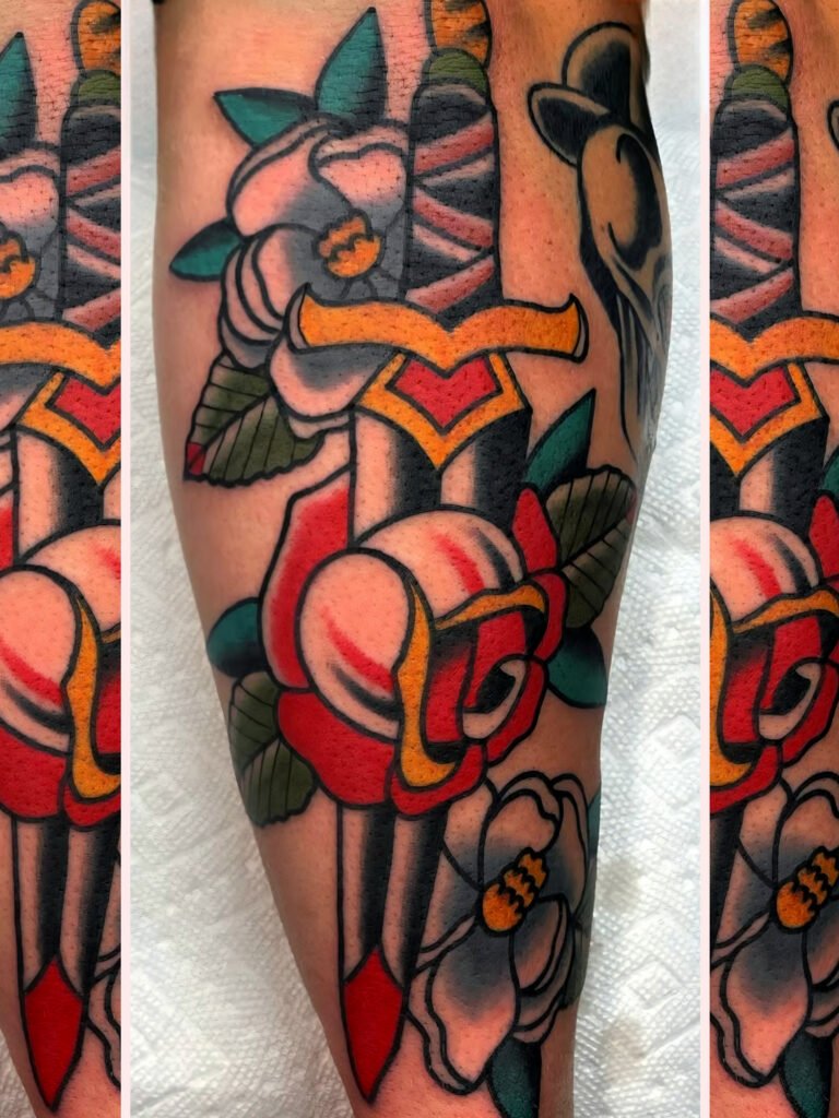 A neo traditional dagger piercing through a white and red rose. In the background are white flowers. With yellow centers. This tattoo was made by Noah Beach, co owner of Near Me Tattoo at 6721 Bells Ferry Rd Ste D110 Woodstock, Ga. 30189