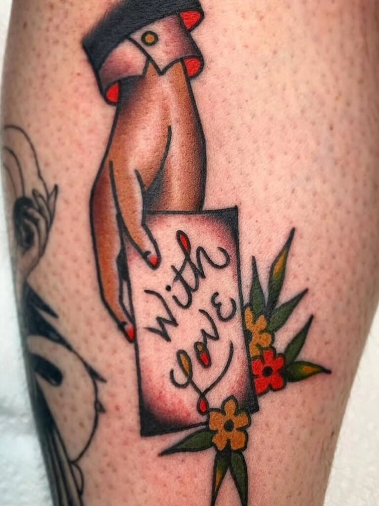 An American traditional tattoo of a hand holding a love letter. On the page of the letter is written “with love” the cuff of the hand has a suit jacket and dress shirt and around the letter are three small flowers with long leaves. This tattoo was made by Noah Beach, co owner of Near Me Tattoo at 6721 Bells Ferry Rd Ste D110 Woodstock, Ga. 30189