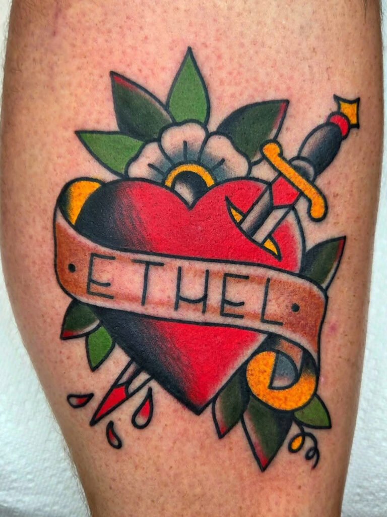 and American traditional heart with dagger going through it. It has a name banner that reads “Ethel” and a white poppy flower. Very bold colored ink. This tattoo was made by Noah Beach, co owner of Near Me Tattoo at 6721 Bells Ferry Rd Ste D110 Woodstock, Ga. 30189