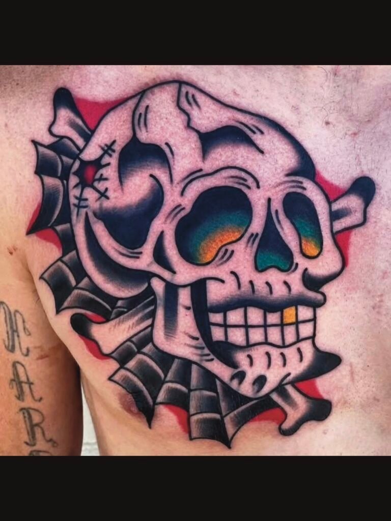 a stylized American traditional style skull and crossbones tattoo. It has a gold tooth with a yellow glow coming from the eyes fading into a deep teal green color. There is a bullet hole in the back of the skull and behind the skull are spider webs. It is done on the chest of a man. This tattoo was made by Noah Beach, co owner of Near Me Tattoo at 6721 Bells Ferry Rd Ste D110 Woodstock, Ga. 30189