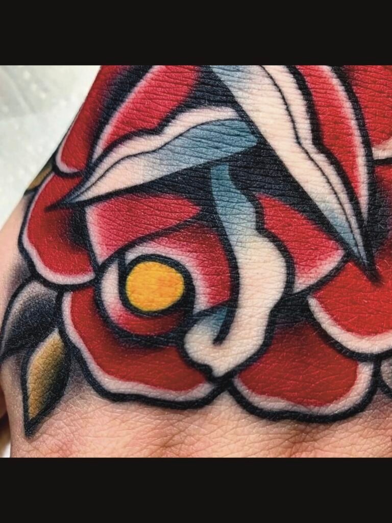 a close up of a Neo traditional or American traditional rose on the top of a hand. It is deep red with a yellow center. The upturned petals are white and the leaves are olive green and black. This tattoo was made by Noah Beach, co owner of Near Me Tattoo at 6721 Bells Ferry Rd Ste D110 Woodstock, Ga. 30189