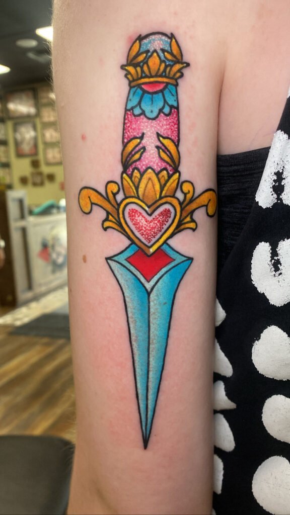 A Neo traditional style dagger tattoo but themed after the Japanese anime Sailor Moon and the characters scepter. The dagger has a glitter ink effect to it that makes it look like it is glowing. This tattoo was done by Jeremy Moffitt an artist at Near Me Tattoo located at 6721 Bells Ferry Rd Ste D110 Woodstock, Ga. 30189