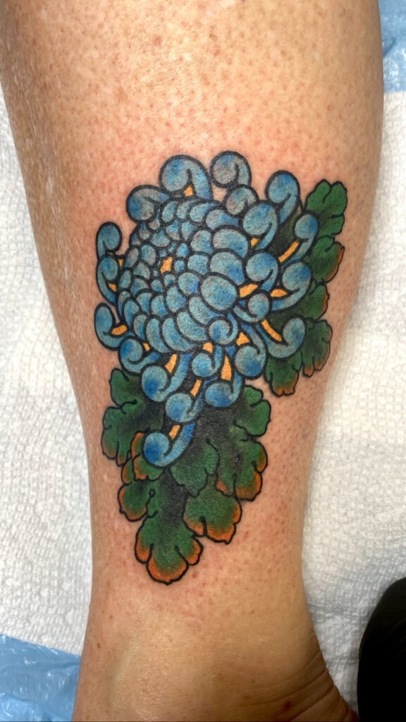 A japanese traditional chrysanthemum or kiku flower tattoo with cool blue colored ink. This tattoo was done by Jeremy Moffitt an artist at Near Me Tattoo located at 6721 Bells Ferry Rd Ste D110 Woodstock, Ga. 30189
