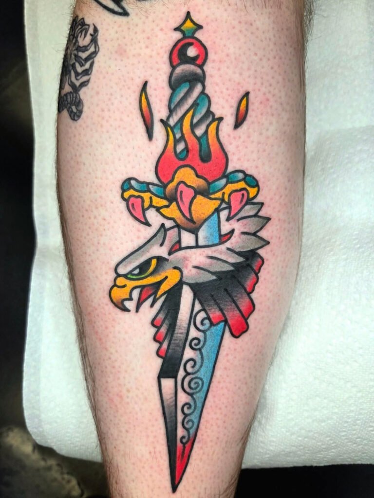 a Neo traditional eagle head being pierced by a dagger. The handle of the dagger is made from an eagle claw and the grip has fire rising up it. This tattoo was made by Noah Beach, co owner of Near Me Tattoo at 6721 Bells Ferry Rd Ste D110 Woodstock, Ga. 30189
