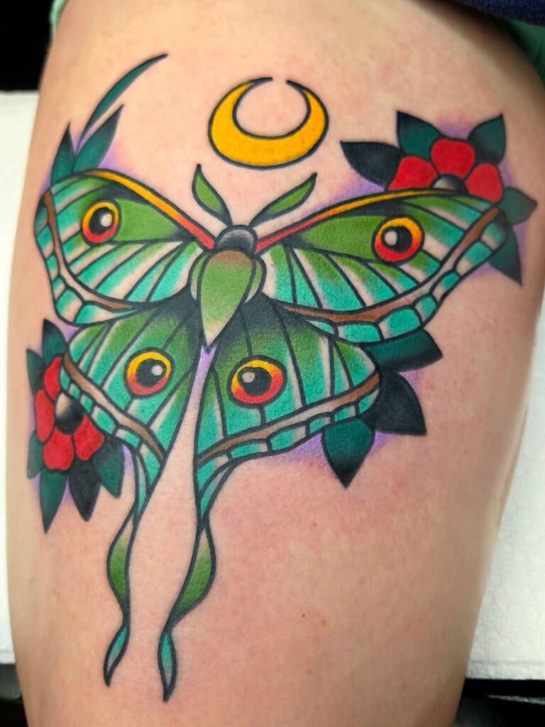 a Neo traditional Luna moth tattoo. The body of the moth has 4 eyes and brightly colored green and blue body with yellow and orange accents. It has two traditional poppy flowers in the background along with a crescent moon at the top. This tattoo was made by Noah Beach, co owner of Near Me Tattoo at 6721 Bells Ferry Rd Ste D110 Woodstock, Ga. 30189