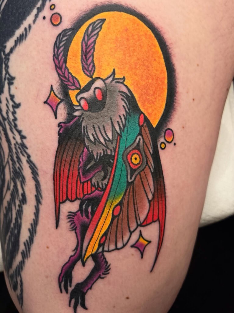 a Neo traditional Mothman tattoo from American folklore. It has a brightly colored mothman with iridescent inspired moth wings and a moths head and antenna. The mothman is in front of a large full moon. This tattoo was made by Noah Beach, co owner of Near Me Tattoo at 6721 Bells Ferry Rd Ste D110 Woodstock, Ga. 30189