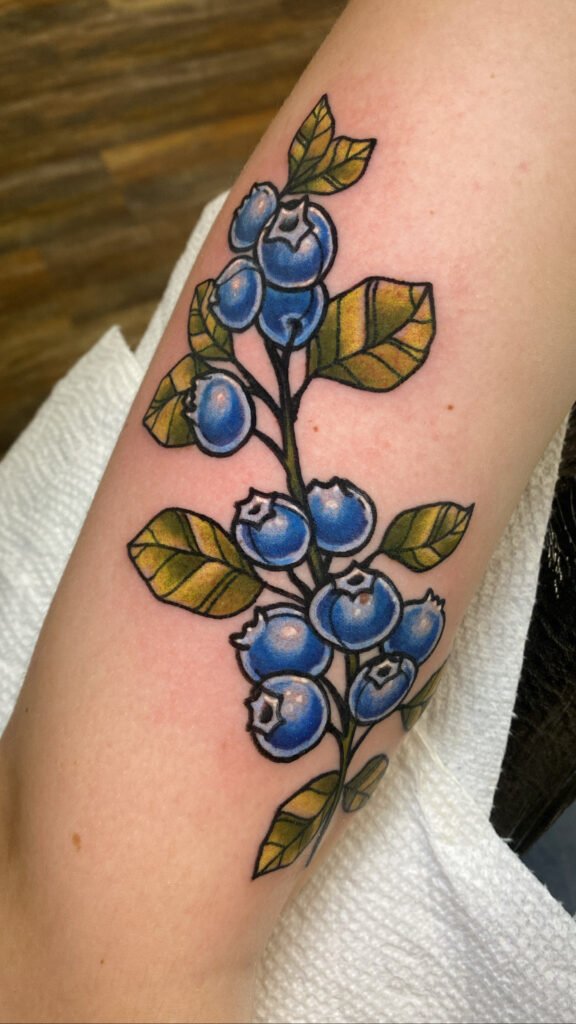 A neo traditional tattoo of a blueberry branch or vine. It has olive colored leaves with deep blue in the berries. The design wraps around the wrist of the client. This tattoo was done by Jeremy Moffitt an artist at Near Me Tattoo located at 6721 Bells Ferry Rd Ste D110 Woodstock, Ga. 30189