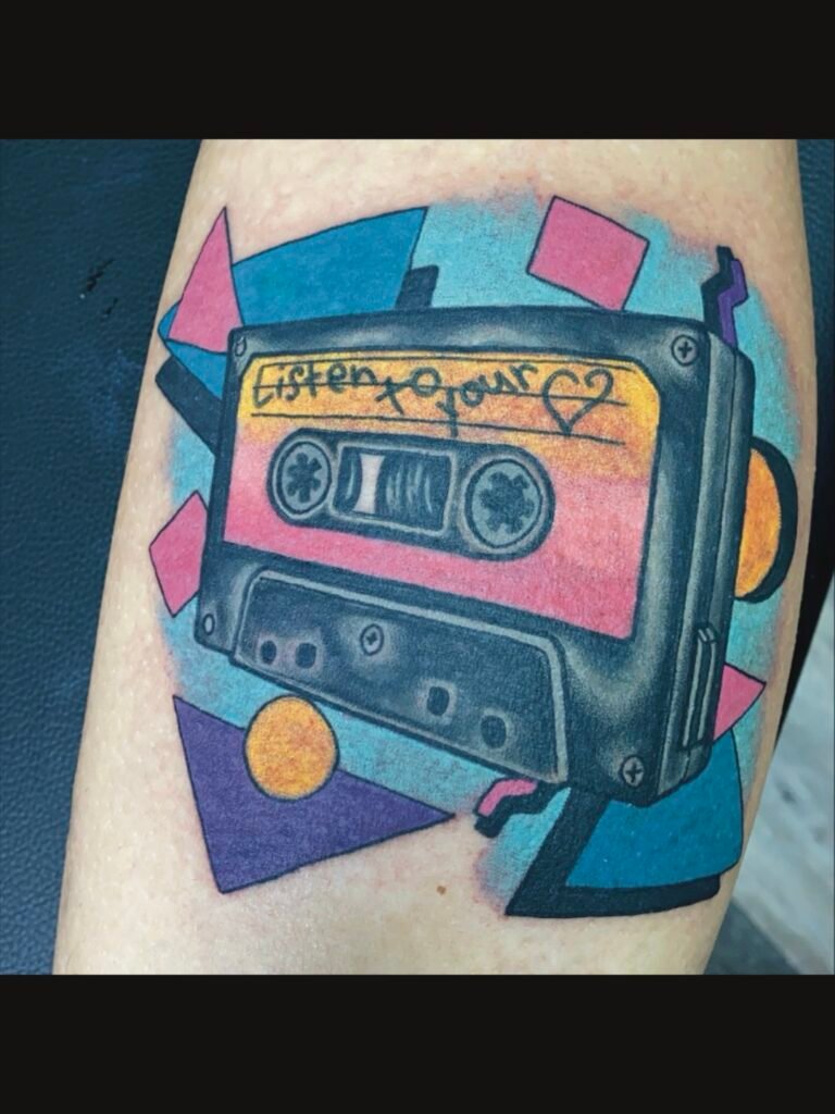 an illustrative tattoo of a black mix tape with a yellow and pink sticker that has the handwritten words “listen to your heart” and a heart on the label. In the background is a 90s pattern made of pastel colors and shapes. This tattoo was done by Jeremy Moffitt an artist at Near Me Tattoo located at 6721 Bells Ferry Rd Ste D110 Woodstock, Ga. 30189