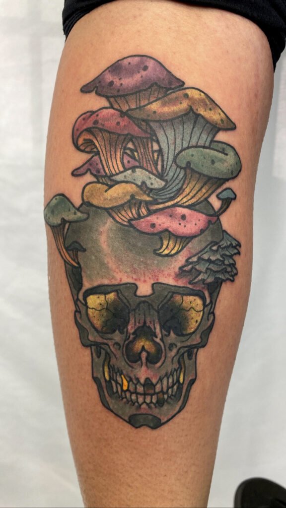 A Neo traditional skull with mushrooms growing out of it tattoo. The ink is muted and earthy. The opaque grey used in the skull gives it a more grounded look and contrasts with he color of the fungi. This tattoo was done by Jeremy Moffitt an artist at Near Me Tattoo located at 6721 Bells Ferry Rd Ste D110 Woodstock, Ga. 30189