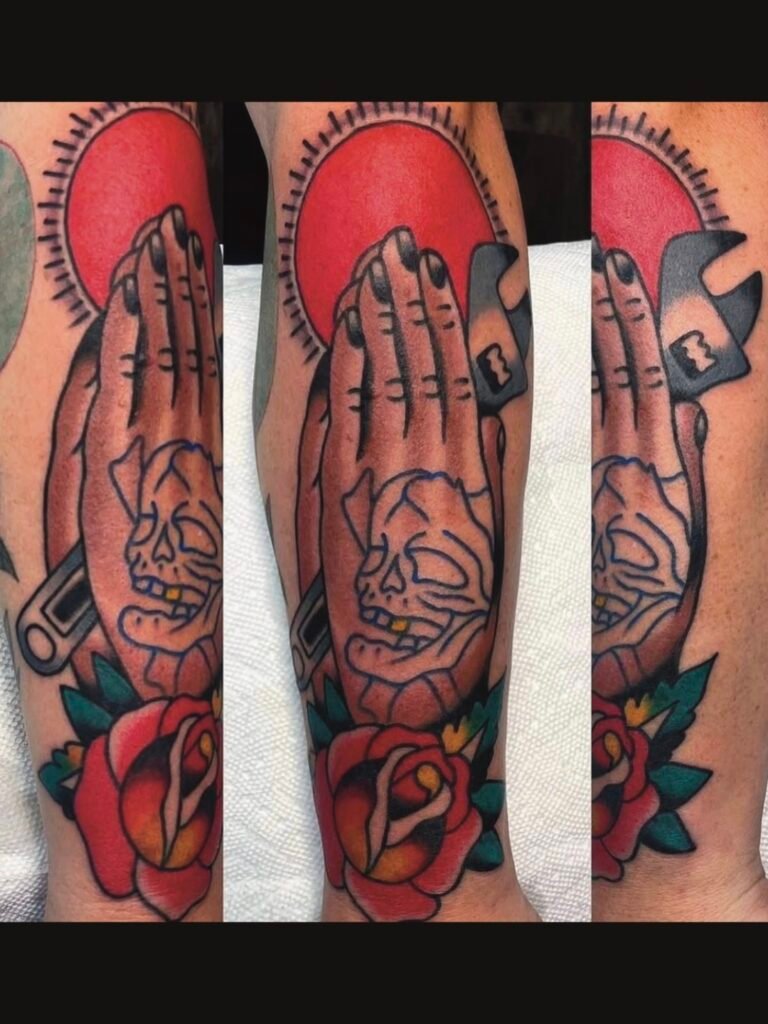 An American traditional tattoo of praying hands with an adjustable wrench. The hands have a traditional blue tattoo of a skull and crossbones. There is a traditional red sun with rays and a traditional mustache rose tattoo at the bottom. This tattoo was made by Noah Beach, co owner of Near Me Tattoo at 6721 Bells Ferry Rd Ste D110 Woodstock, Ga. 30189