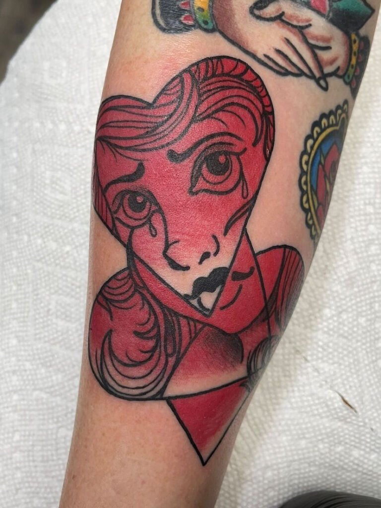 a new school geometric abstract tattoo made of an overlay of hearts and inside of the hearts is a woman’s face. It is done all in black lines and simple red shading to add depth. This tattoo was done by Jeremy Moffitt an artist at Near Me Tattoo located at 6721 Bells Ferry Rd Ste D110 Woodstock, Ga. 30189