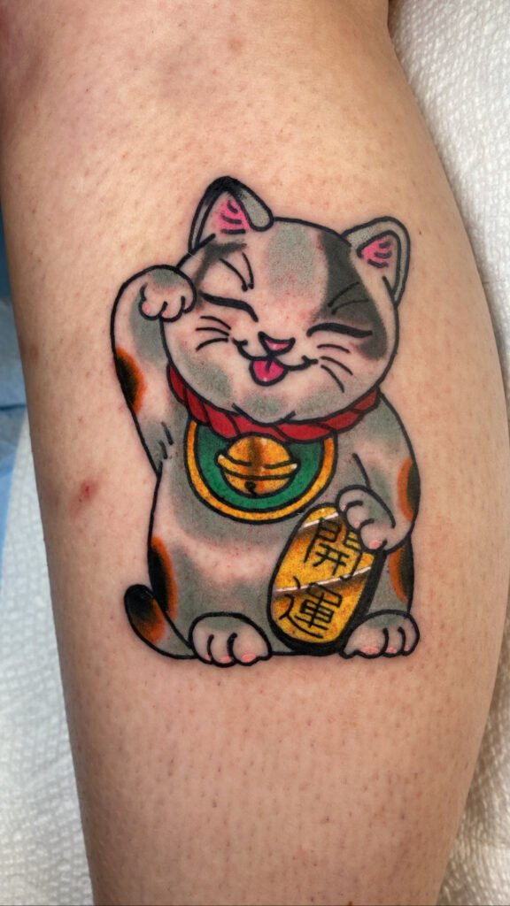 a neo traditional Japanese norinco tattoo. The lucky cat has a gold money piece and is doing the traditional wave. It is a calico with different rust and grey colored ink for the animals markings. This tattoo was done by Jeremy Moffitt an artist at Near Me Tattoo located at 6721 Bells Ferry Rd Ste D110 Woodstock, Ga. 30189