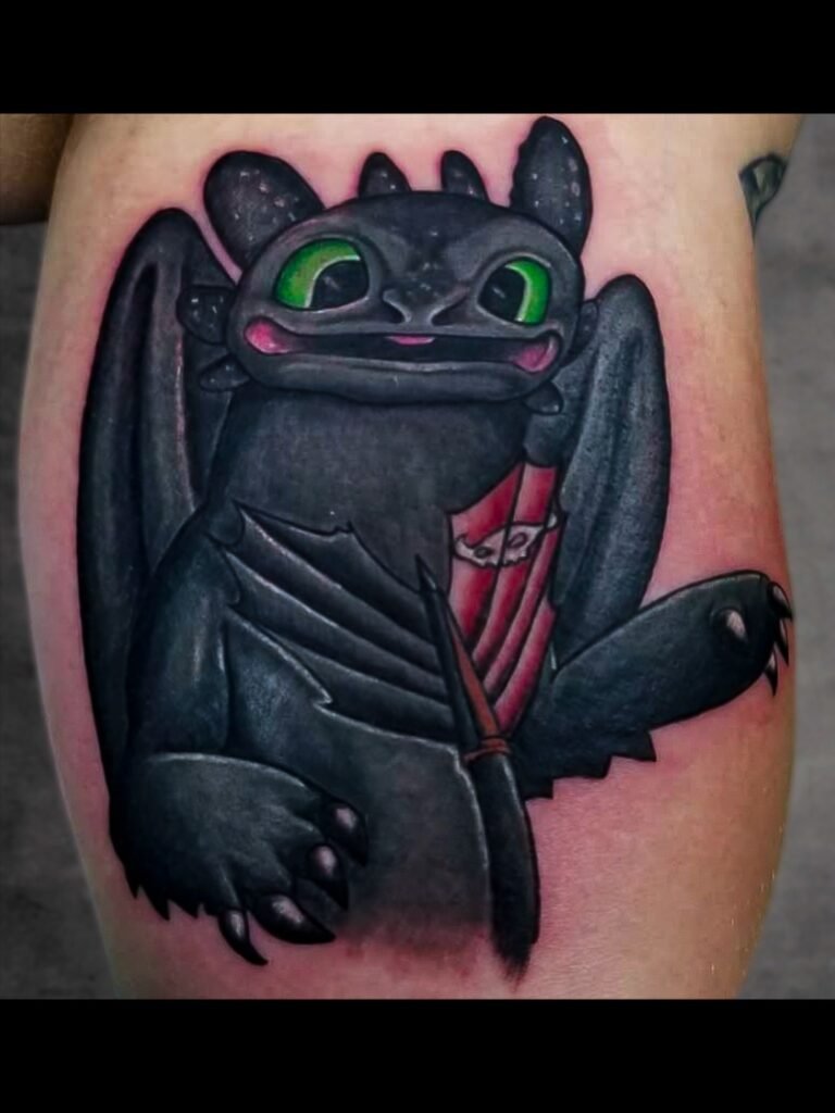 A color semi realistic ink tattoo of Toothless the dragon from how to train your pet dragon series. It is a realistic take on the cartoon character. It has his bright green ink colored eyes and tail with the fixed fin with the Viking skull on it. This tattoo was made by Nathan Heinrich, co owner of Near Me Tattoo at 6721 Bells Ferry Rd Ste D110 Woodstock, Ga. 30189