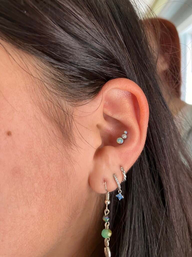 A picture of a conch piercing done on the ear of the wearer. It is a very popular ear piercing for both men and women. The jewelry used is titanium with a triple cluster of cz stones. This piercing was done by Hope Boyd the body piercer at Near Me Tattoo at 6721 Bells Ferry Rd STE D110 Woodstock, Georgia 30189