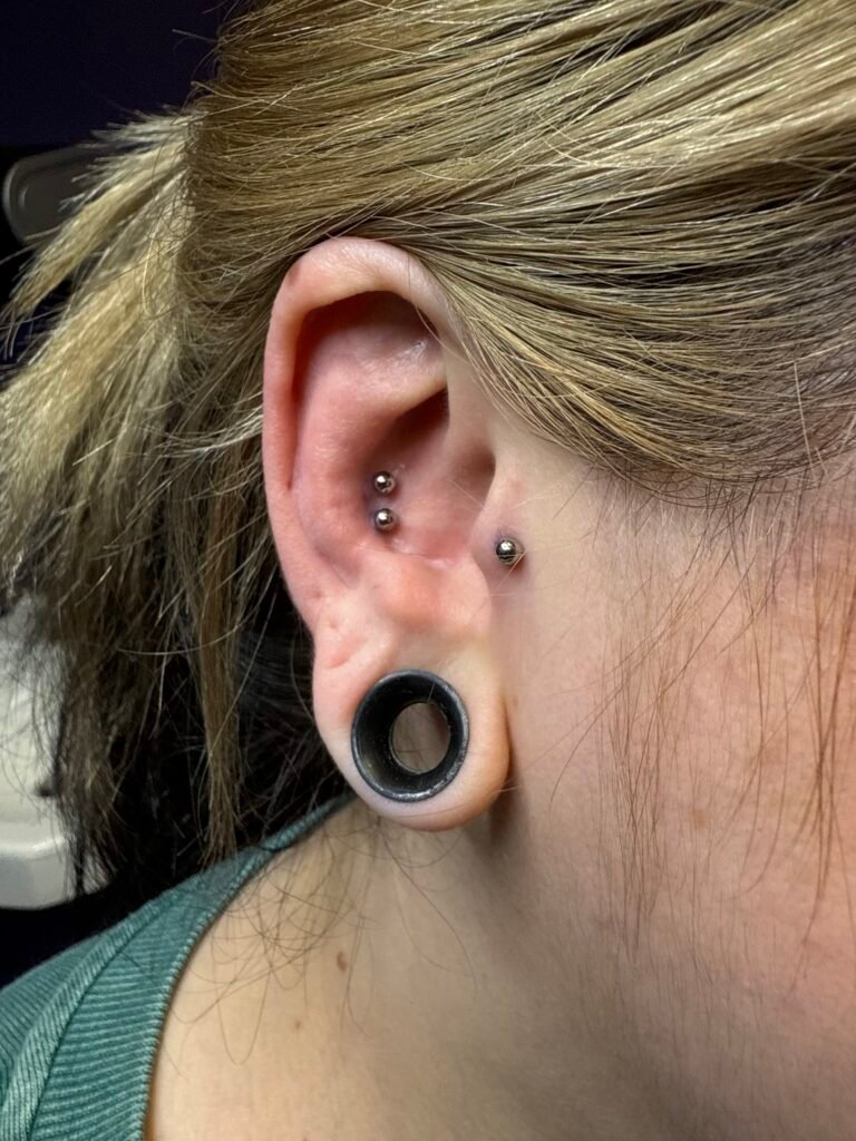 A picture of a double conch and tragus piercing done on the same ear of a woman. The piercings are done on one ear. These are some of the most popular ear piercings for both men and women. The jewelry used was titanium. This piercing was done by Hope Boyd the body piercer at Near Me Tattoo at 6721 Bells Ferry Rd STE D110 Woodstock, Georgia 30189