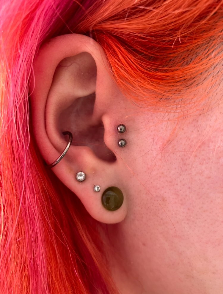 A picture of a double tragus piercing done on a woman’s ear. It is done with titanium jewelry and looks feminine. This is a popular ear piercing for both men and women. This piercing was done by Hope Boyd the body piercer at Near Me Tattoo at 6721 Bells Ferry Rd STE D110 Woodstock, Georgia 30189