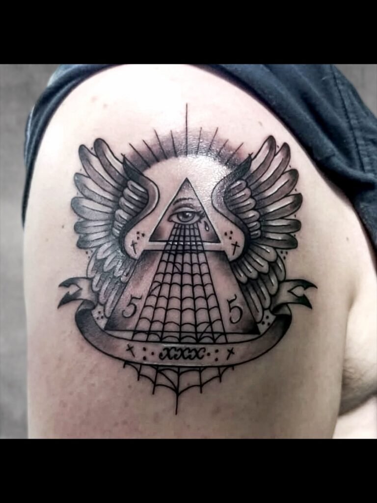 a black and grey or gray ink illustrative tattoo of the all seeing eye. The eye is atop a pyramid with spider webs flowing from the bottom of the eye. The pyramid has wings and a negative space sun. Small symbols adorn the piece including the number 5 repeated twice to represent man. This tattoo was made by Nathan Heinrich, co owner of Near Me Tattoo at 6721 Bells Ferry Rd Ste D110 Woodstock, Ga. 30189