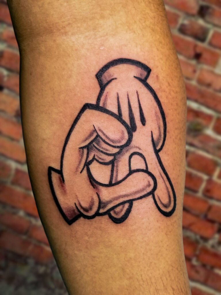 An illustrative tattoo of cartoon character hands and fingers forming the initials C and A representing the state of California. It shows cartoon glove hands similar to that of Mickey Mouse or other similar cartoon characters. This tattoo was made by Nathan Heinrich, co owner of Near Me Tattoo at 6721 Bells Ferry Rd Ste D110 Woodstock, Ga. 30189