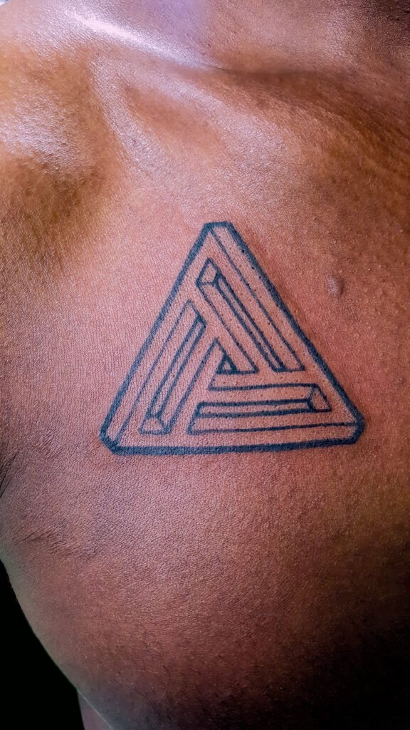 An illustrative style Viking Valknut tattoo on the chest of the wearer below the collar bone. It is done with various line weights of fine, medium, and heavy. It is bold and striking. This tattoo was made by Nathan Heinrich, co owner of Near Me Tattoo at 6721 Bells Ferry Rd Ste D110 Woodstock, Ga. 30189